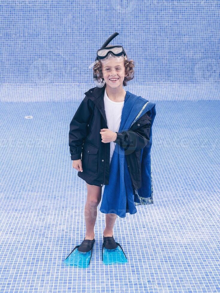 Cheerful boy in mask and flippers in empty pool photo
