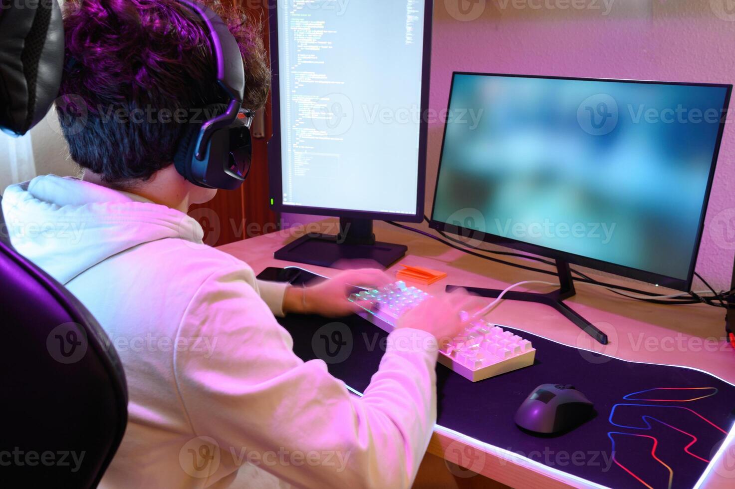 Anonymous young man in headphones playing on keyboard and sitting at table with gadgets photo
