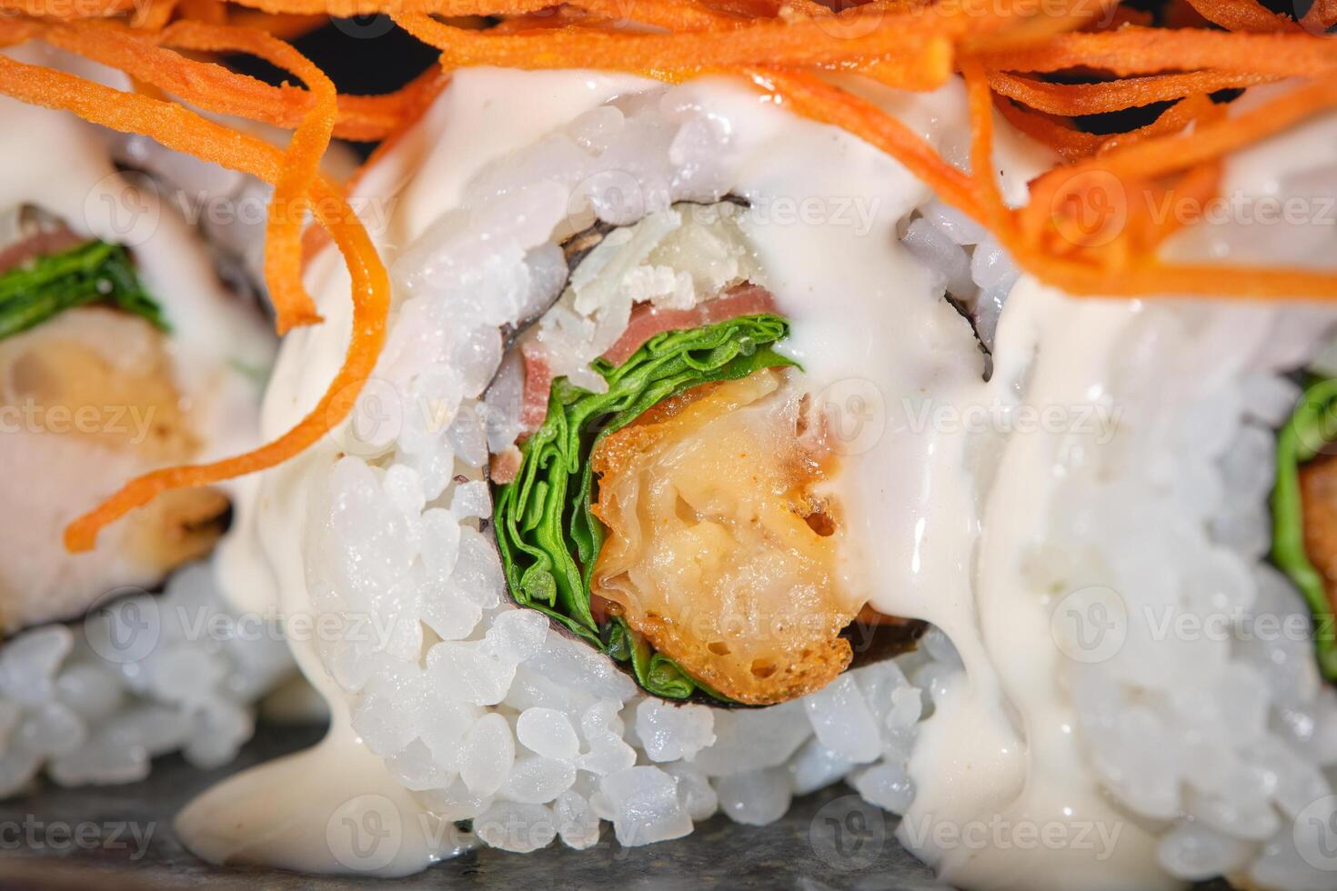 Delicious sushi maki with salmon decorated with shredded carrot and sauce served on plate photo