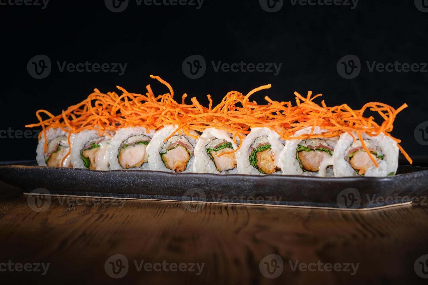 Row of sushi maki with salmon decorated with shredded carrot served on plate photo