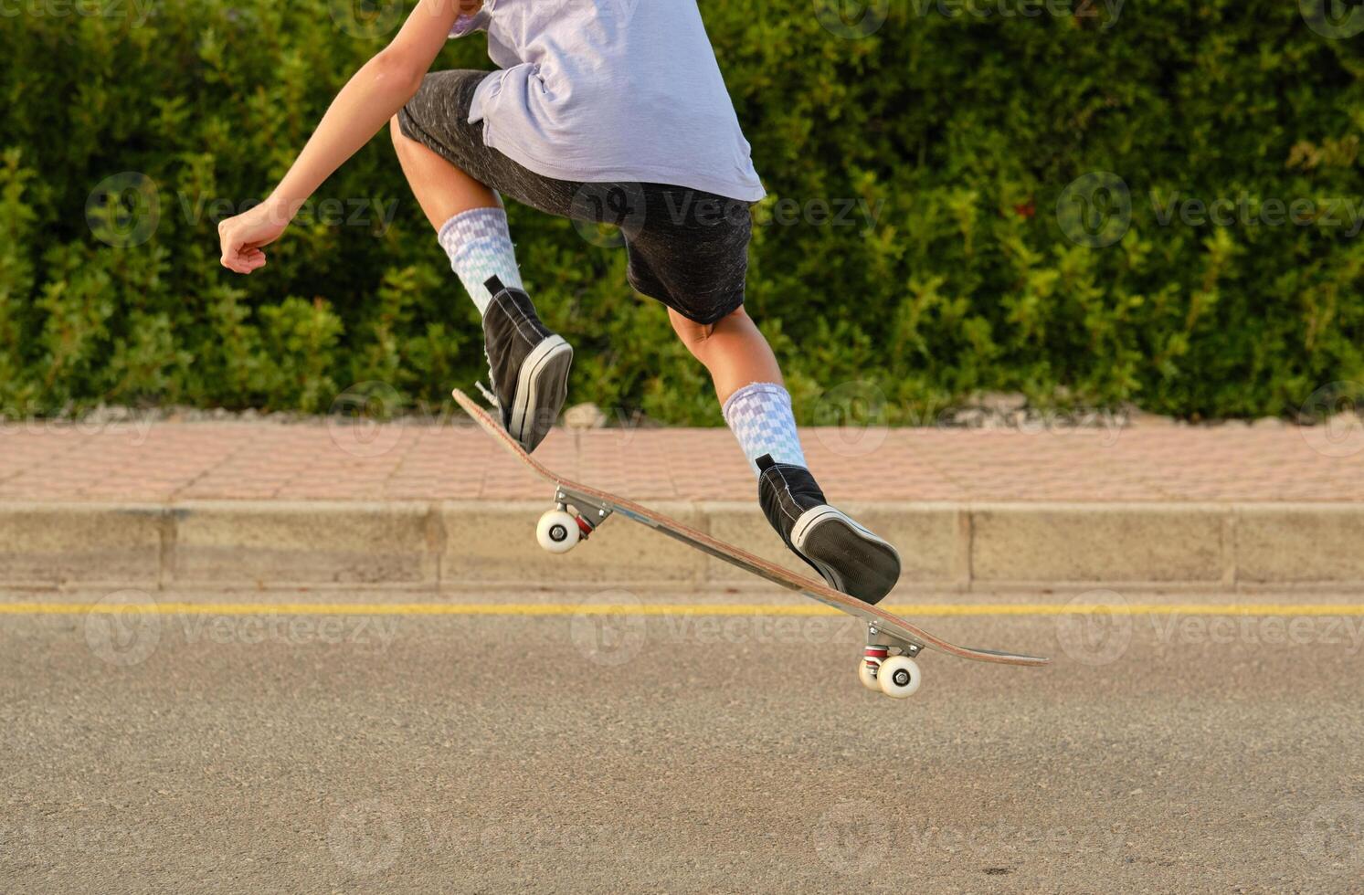 Crop boy jumping with skateboard and showing trick photo
