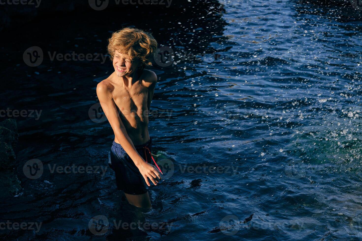 Boy grimacing in wavy sea with splashing water photo