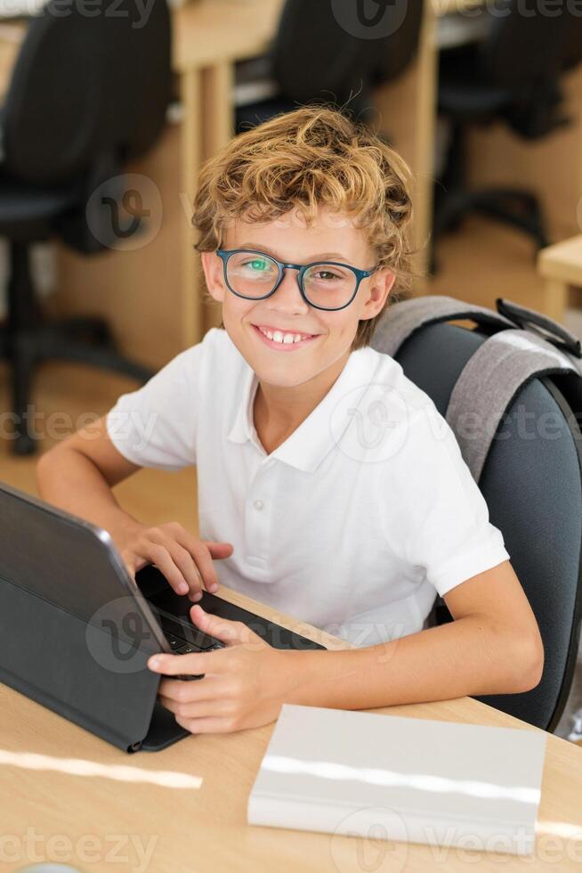 Delighted schoolboy using tablet in classroom photo