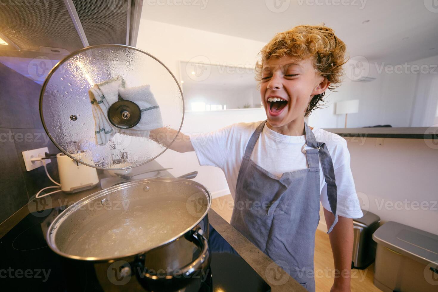 Excited boy with lid against boiling water in pot photo