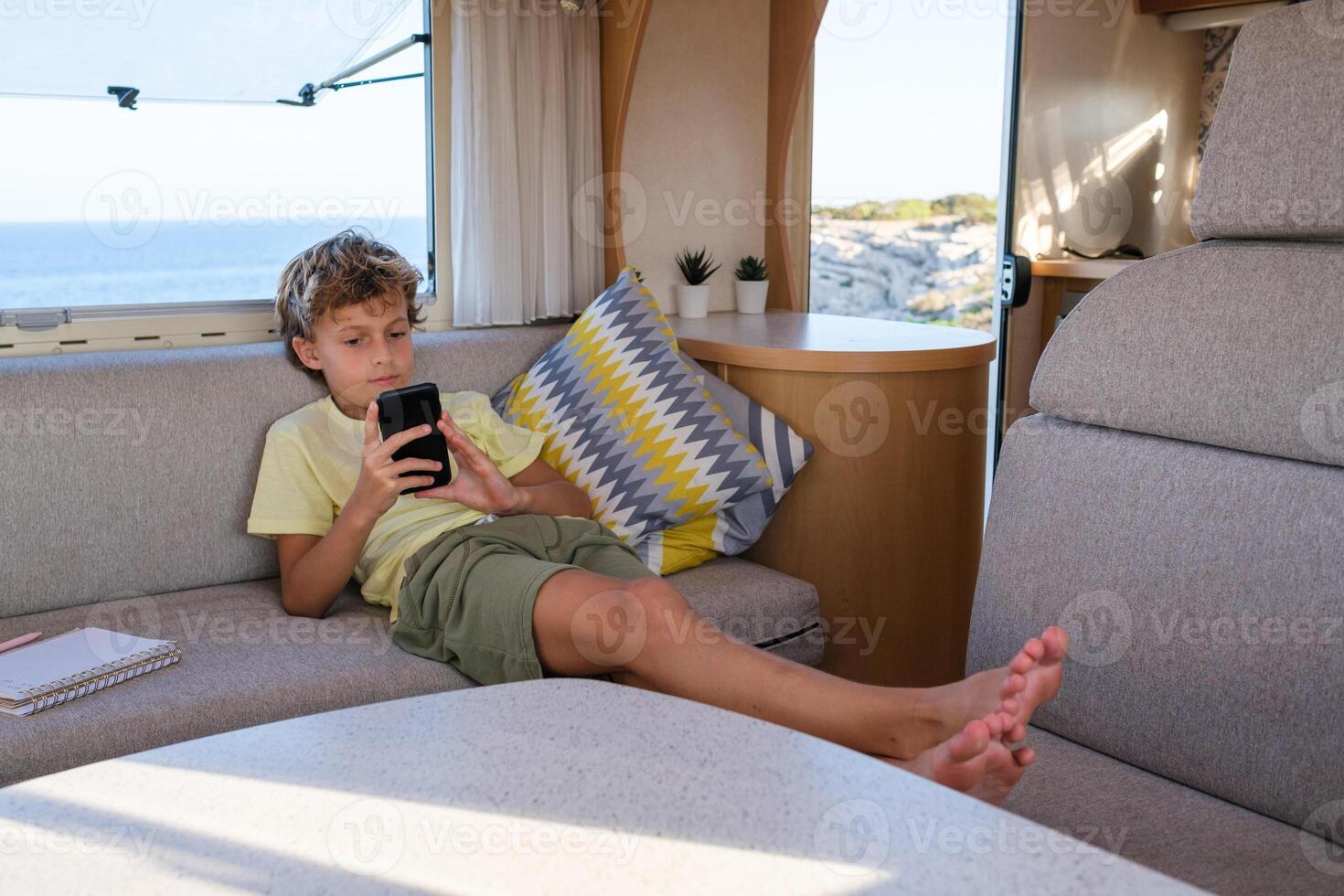 Boy with smartphone chilling in RV photo