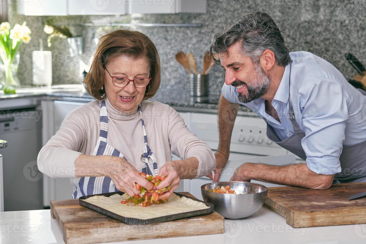 Son and mother cooking pie in kitchen photo