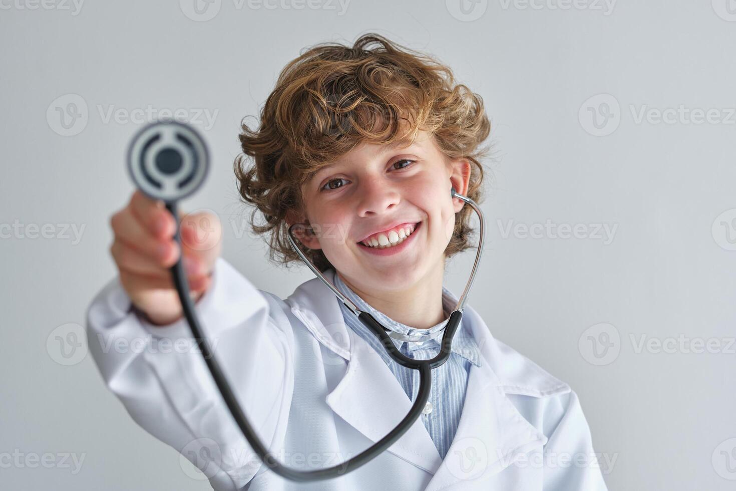 Cheerful boy with stethoscope in medical uniform photo