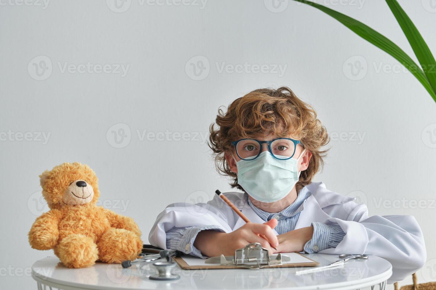 Boy in medical uniform with toy bear during checkup photo
