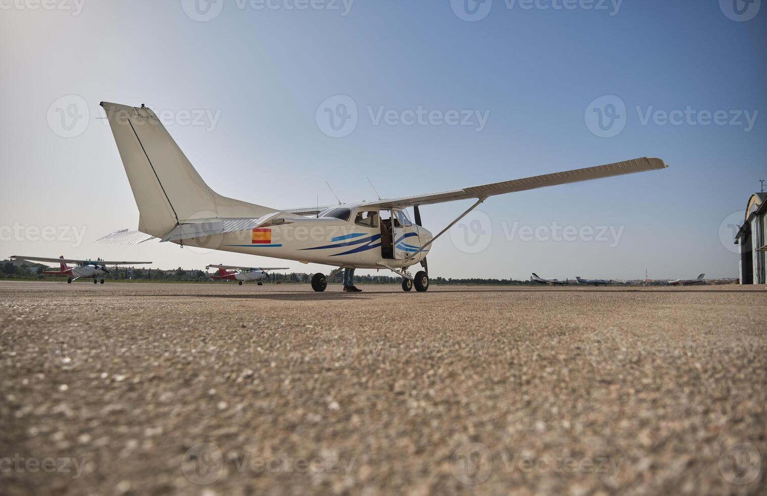 White high wing aircraft parked on runway under blue sky photo
