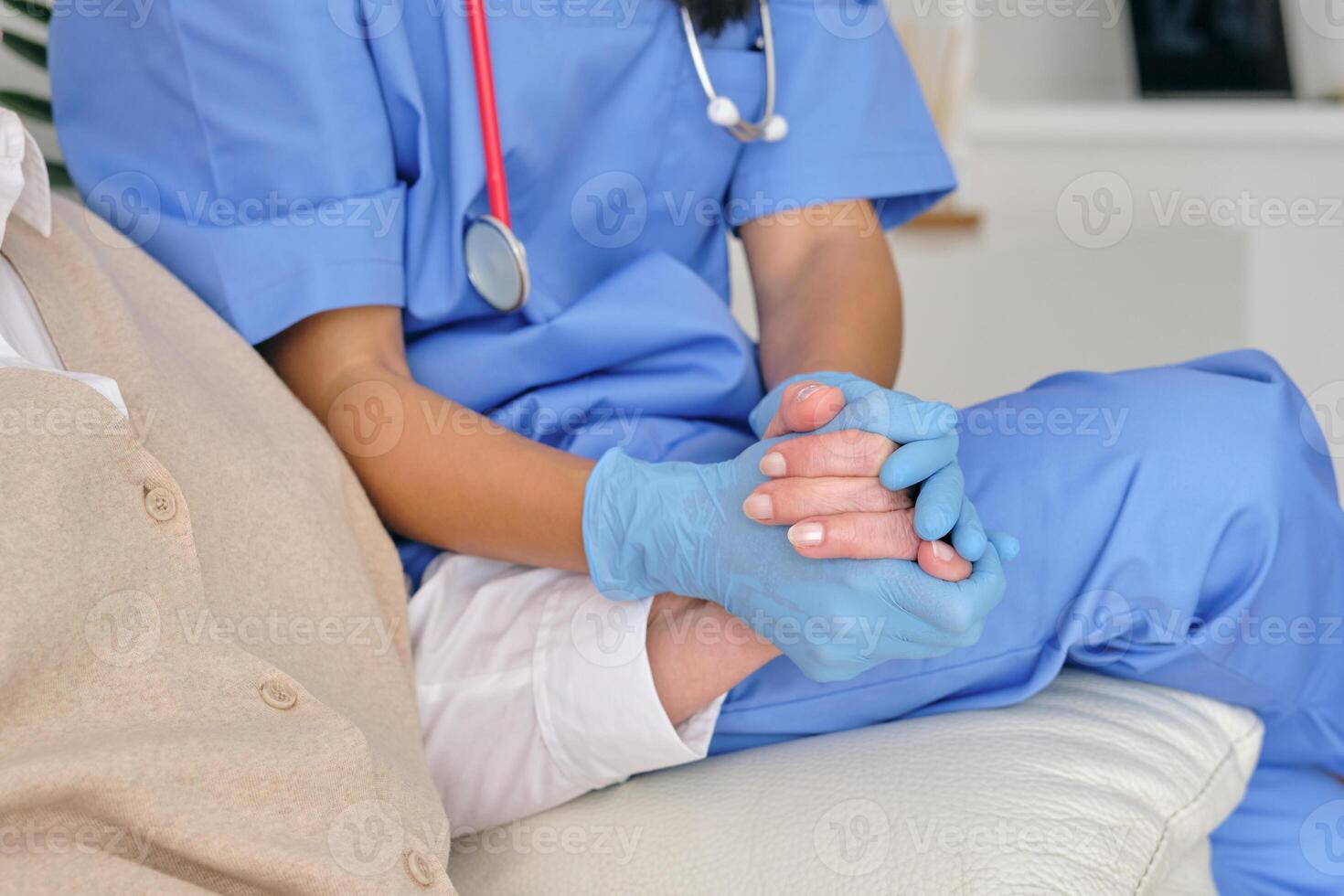Crop physician with patient holding hands during checkup on couc photo