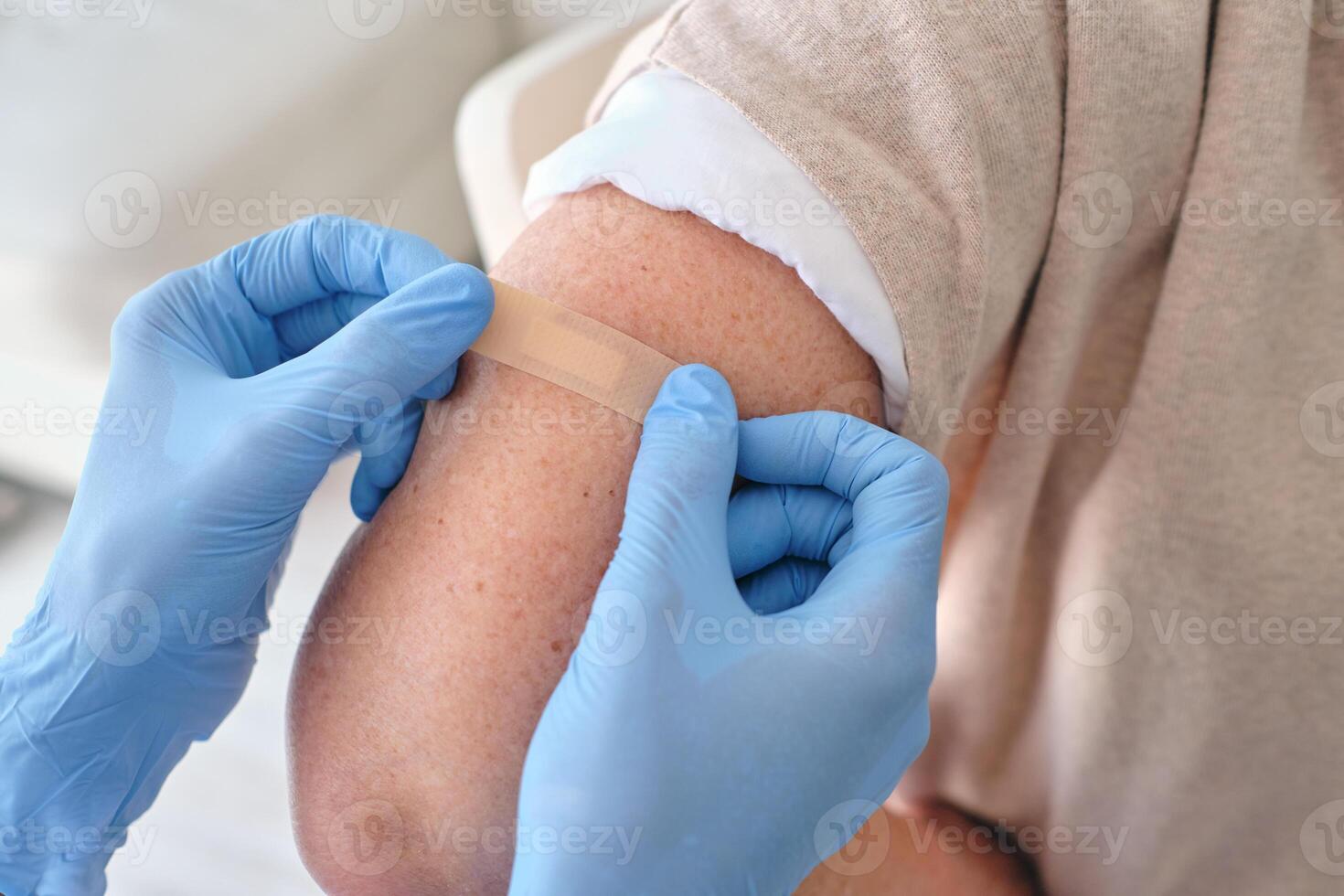 Crop nurse applying medical plaster on arm of patient photo