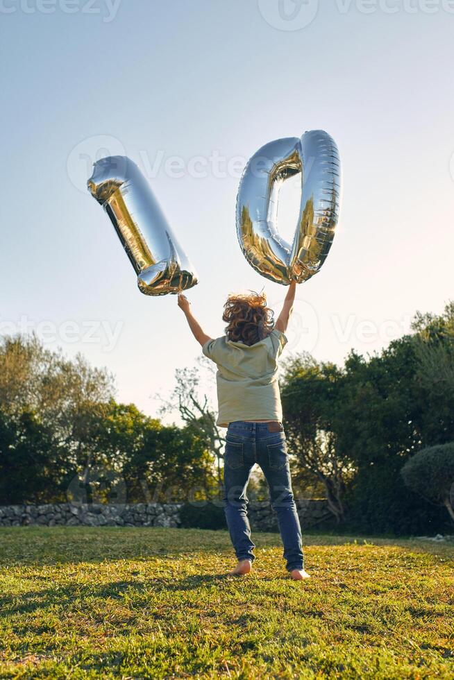 Unrecognizable boy with number balloons during birthday on meado photo