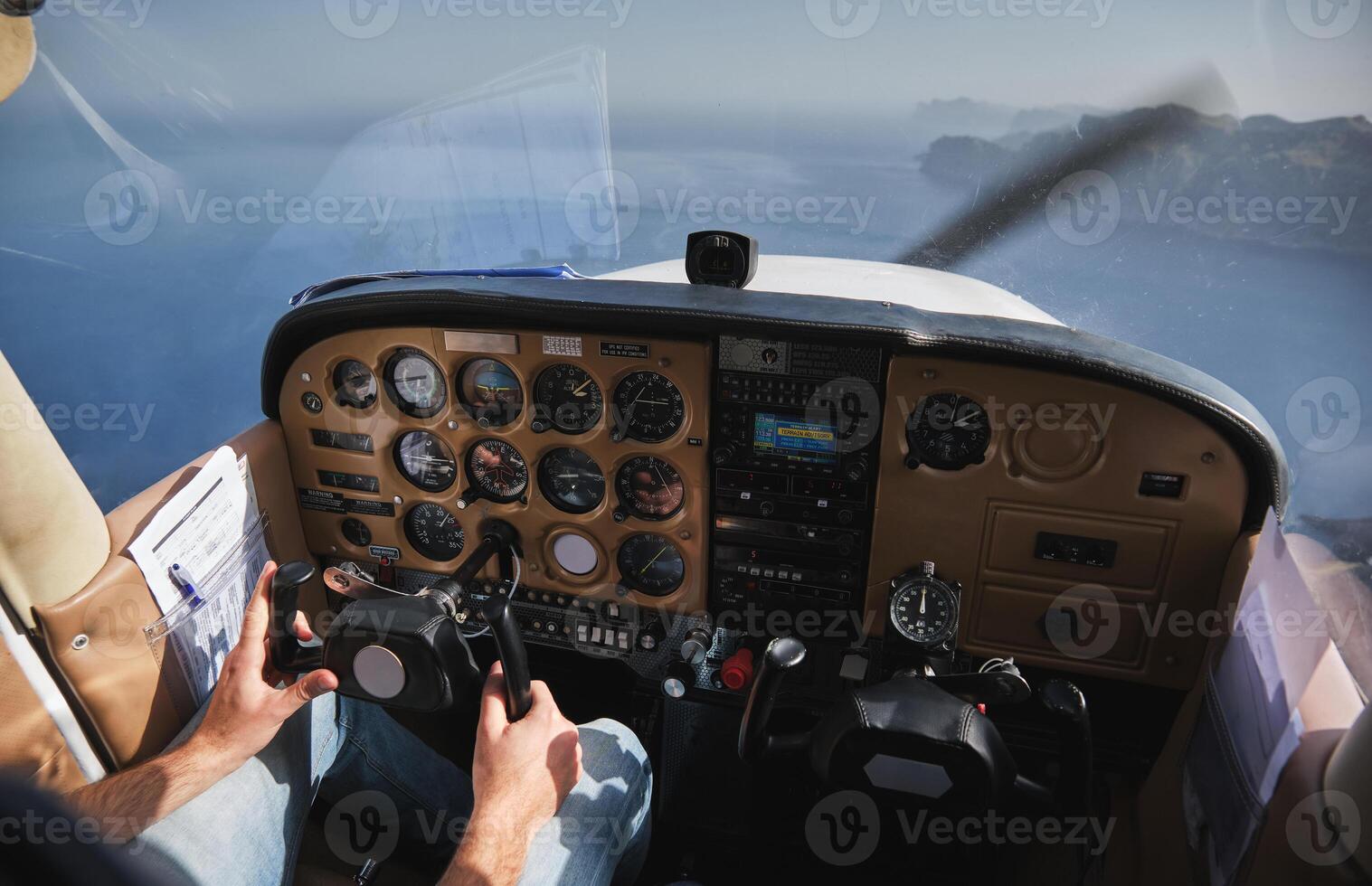 Crop faceless pilot operating biplane above blue sea photo