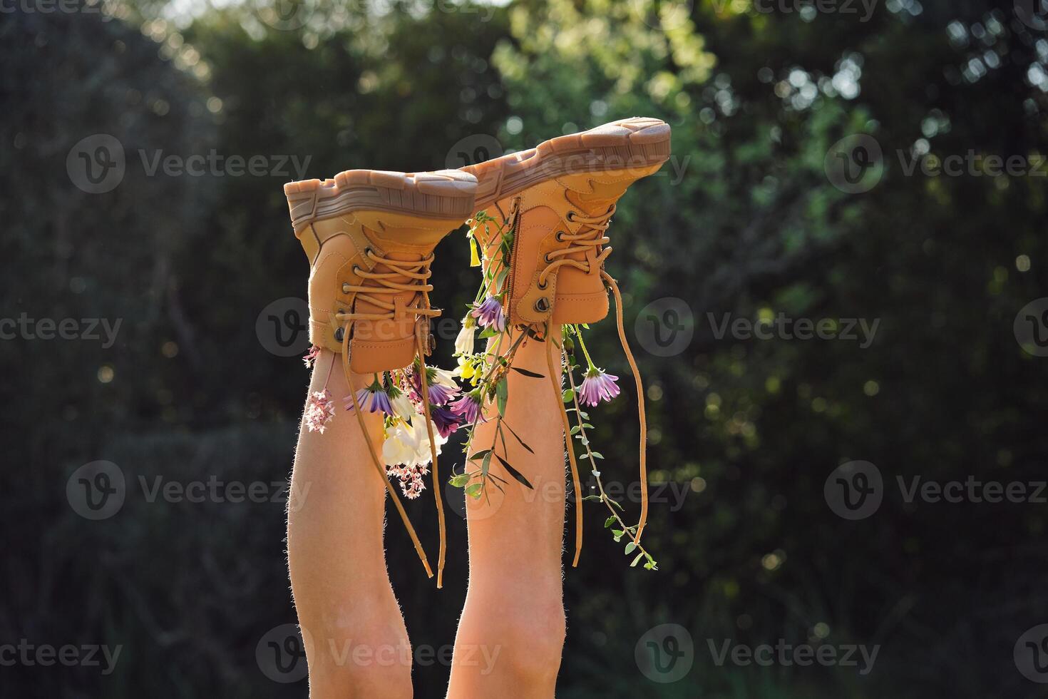 Crop person wearing boots with flowers lying in nature photo