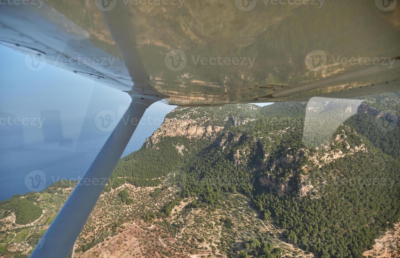 Aircraft view of green mountains and blue sea in sunlight photo