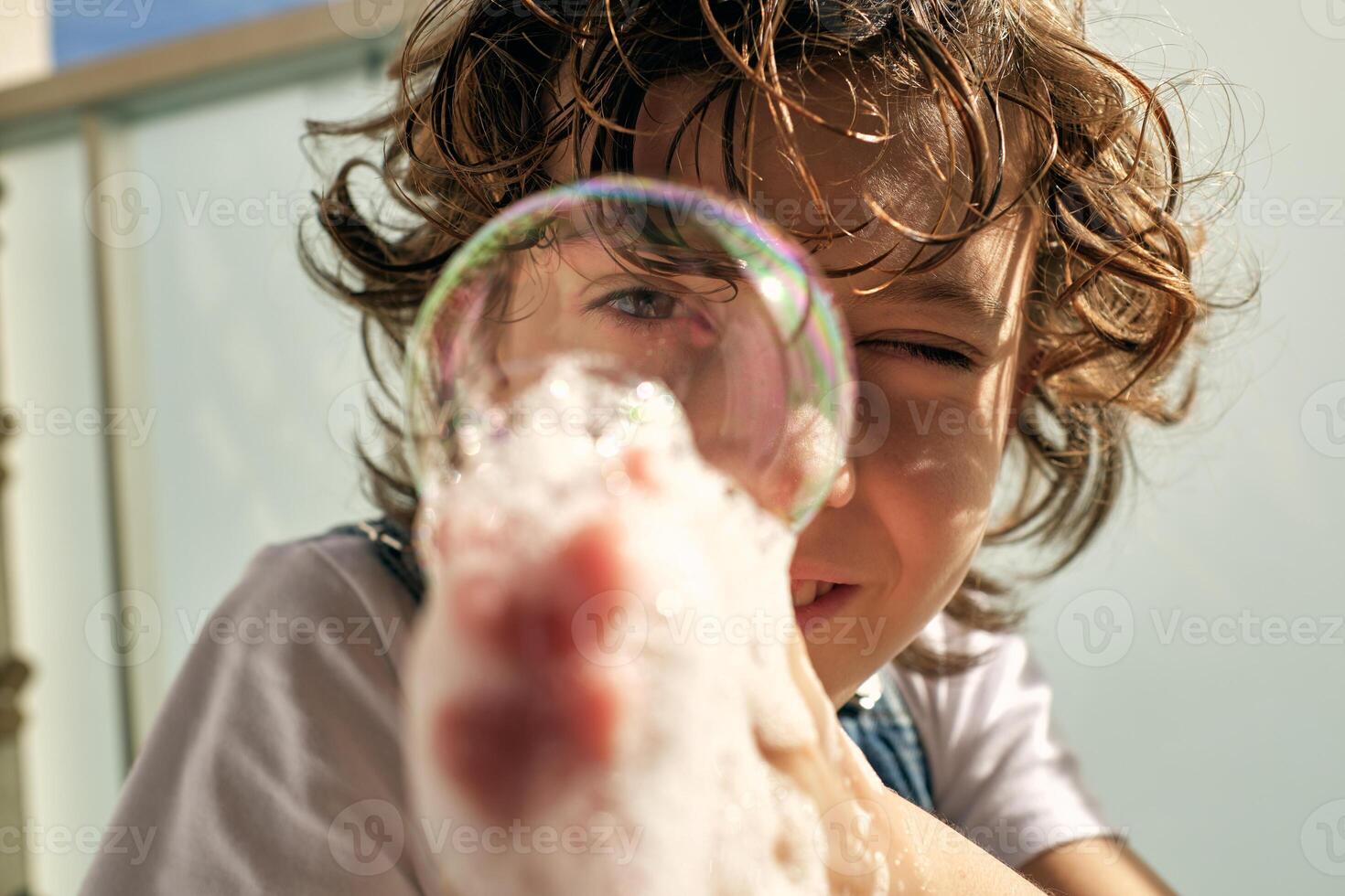 Happy kid blowing bubbles on balcony photo