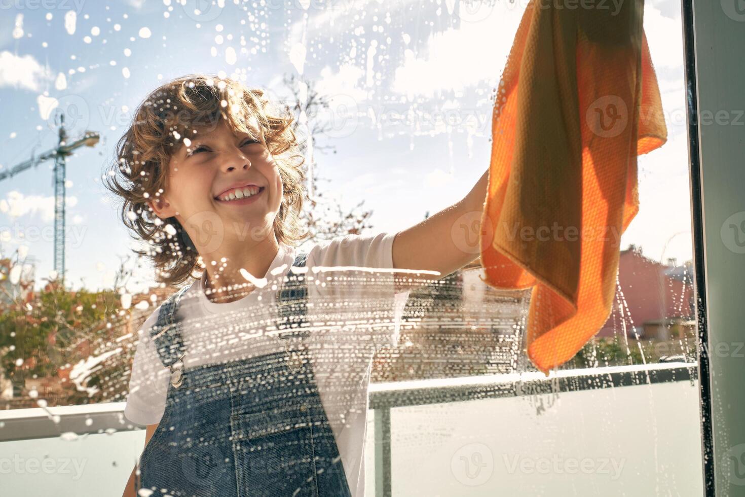 Happy kid cleaning window and smiling photo