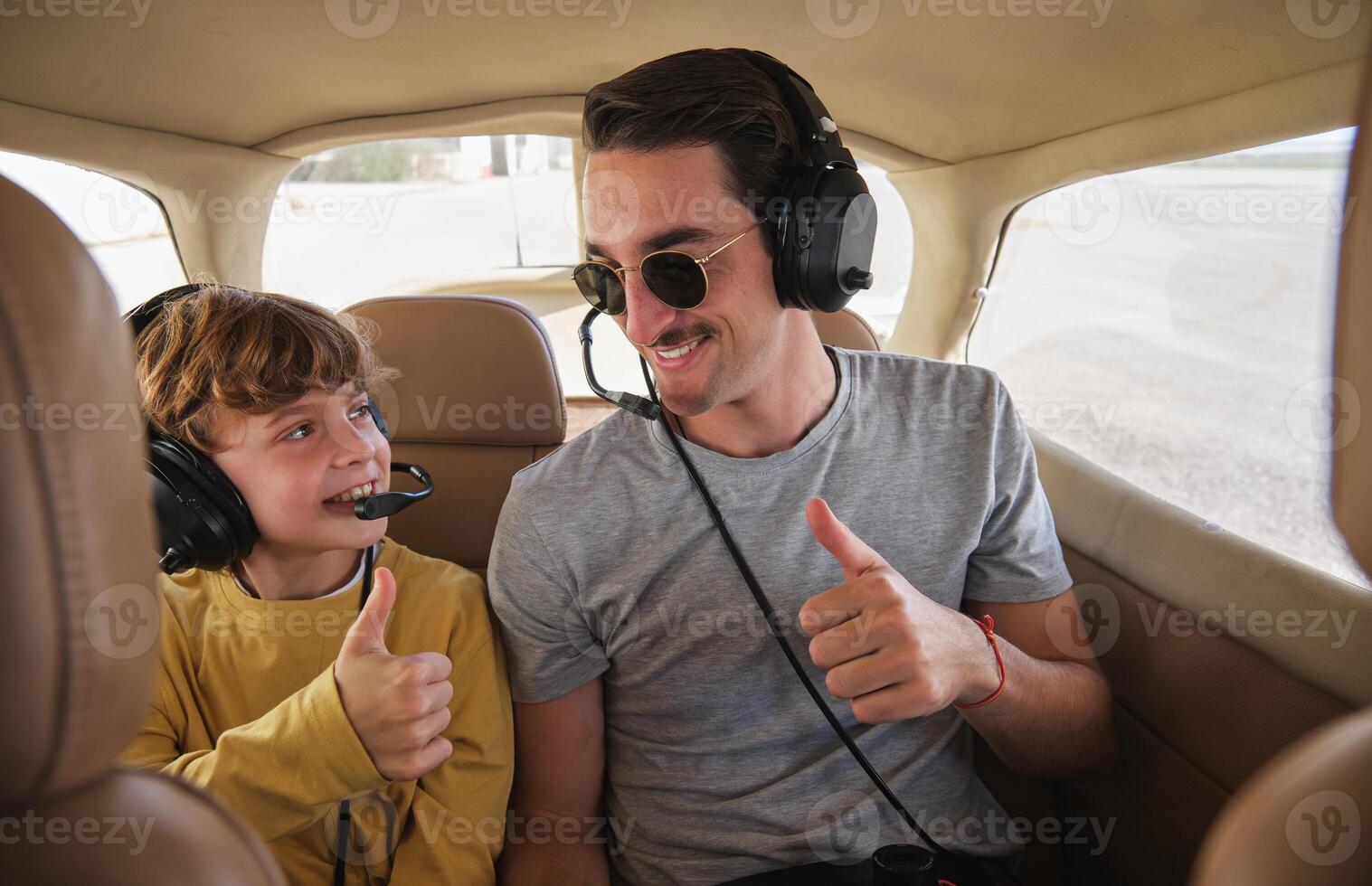 Cheerful young man and child showing thumbs up before flight on photo