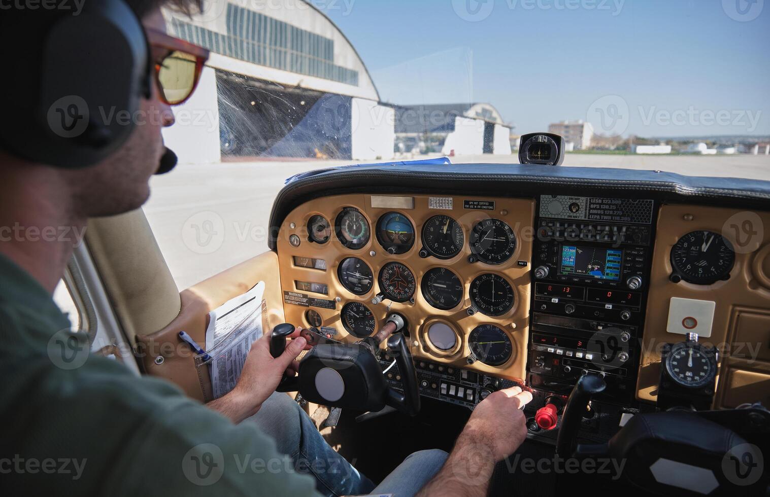 Young male pilot operating airplane parked on airfield on sunny photo