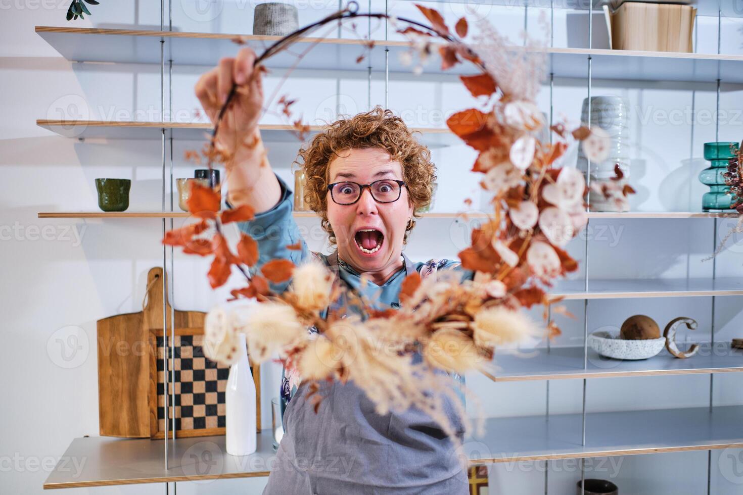 Shocked woman with wreath in hands in workshop photo