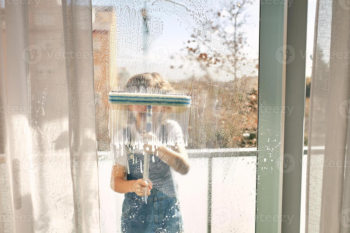 Unrecognizable boy washing windows at home photo