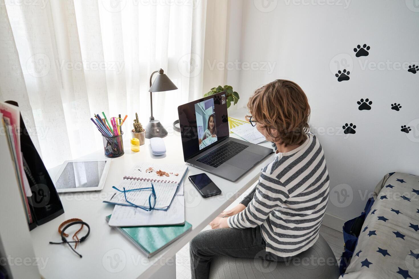 Curly haired boy talking on chat with classmate at home photo