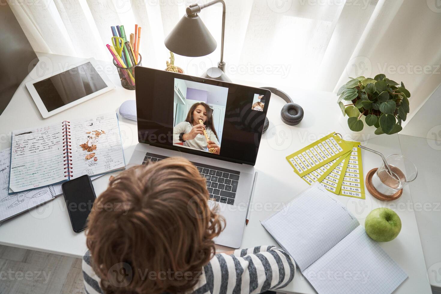 Boy chatting on laptop with girl playing flute photo