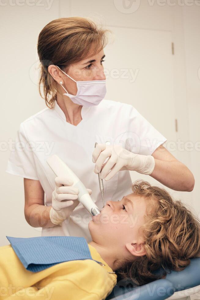 Woman scanning teeth of boy in medical office photo