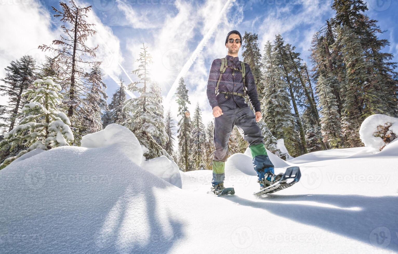 Confident young man trekking in snowshoes over snow in Yosemite California photo