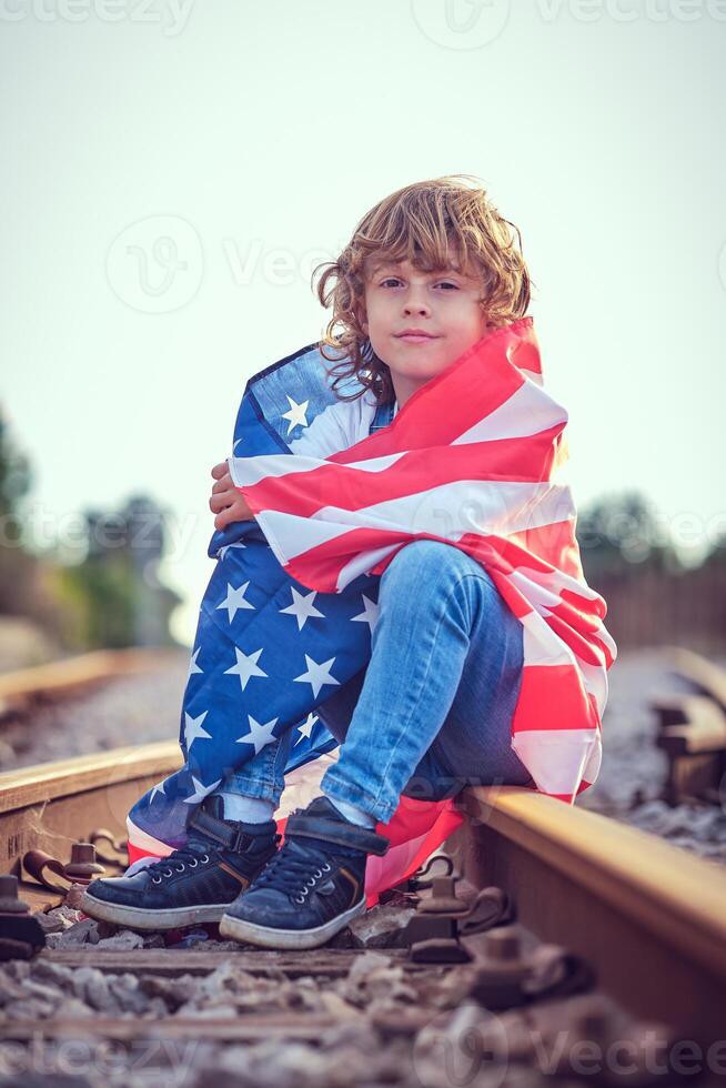 Kid wrapped in USA flag on railway photo