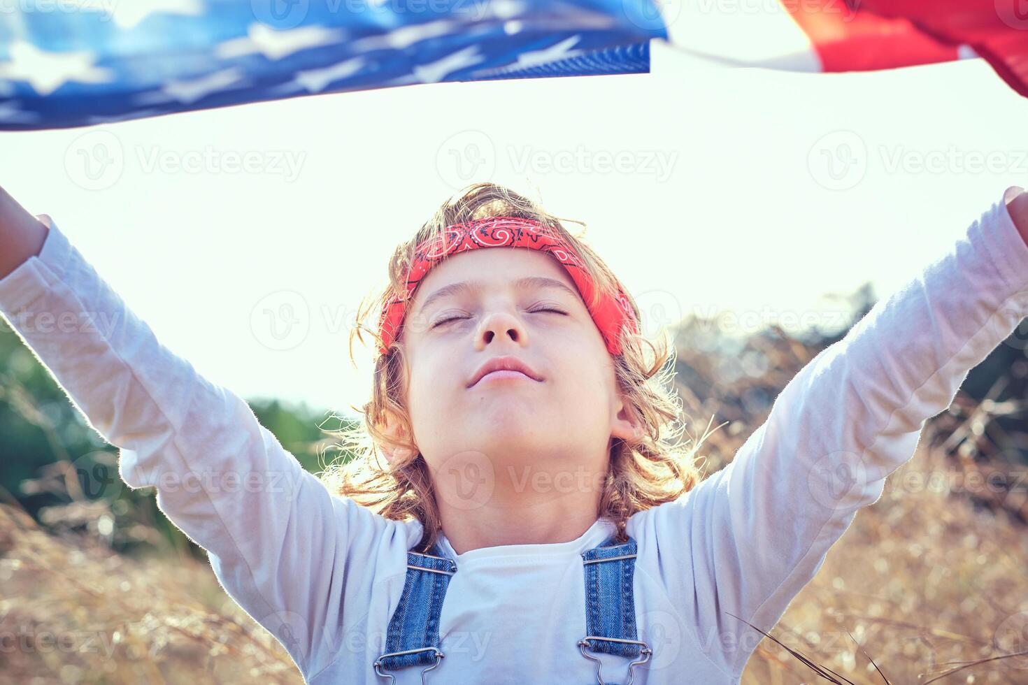 Calm preteen boy with raised hands and waving American flag photo