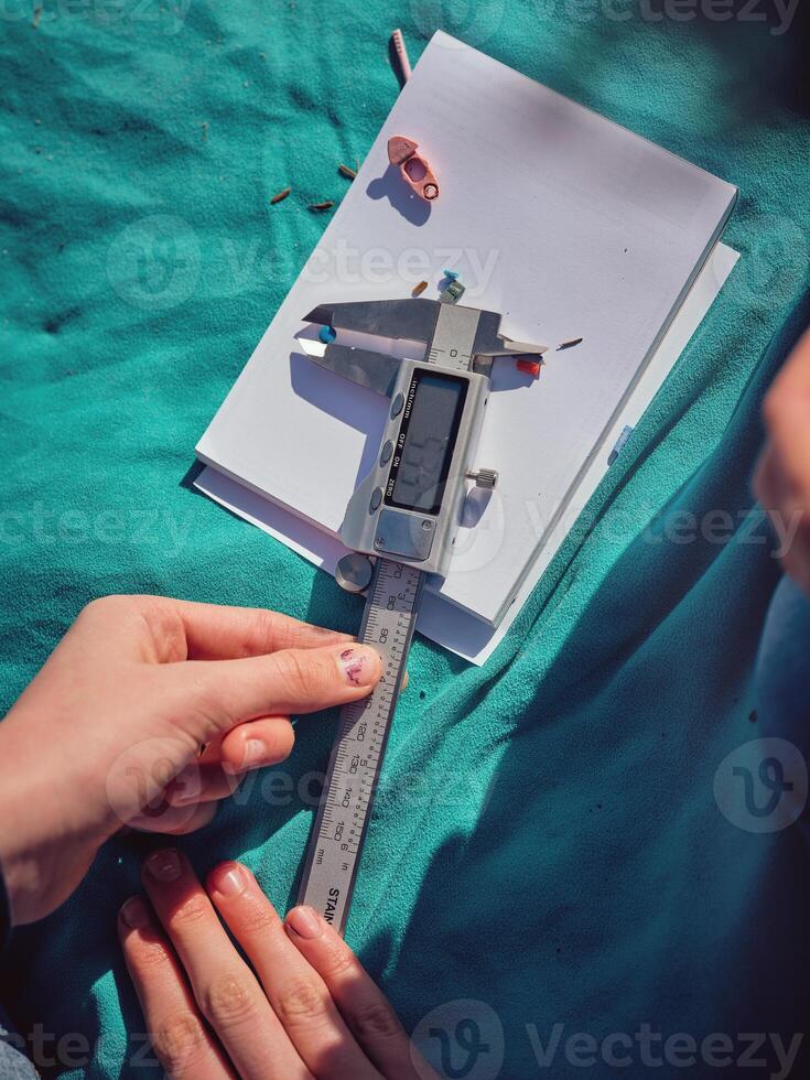 Crop preteen girl adjusting digital caliper while measuring plas photo