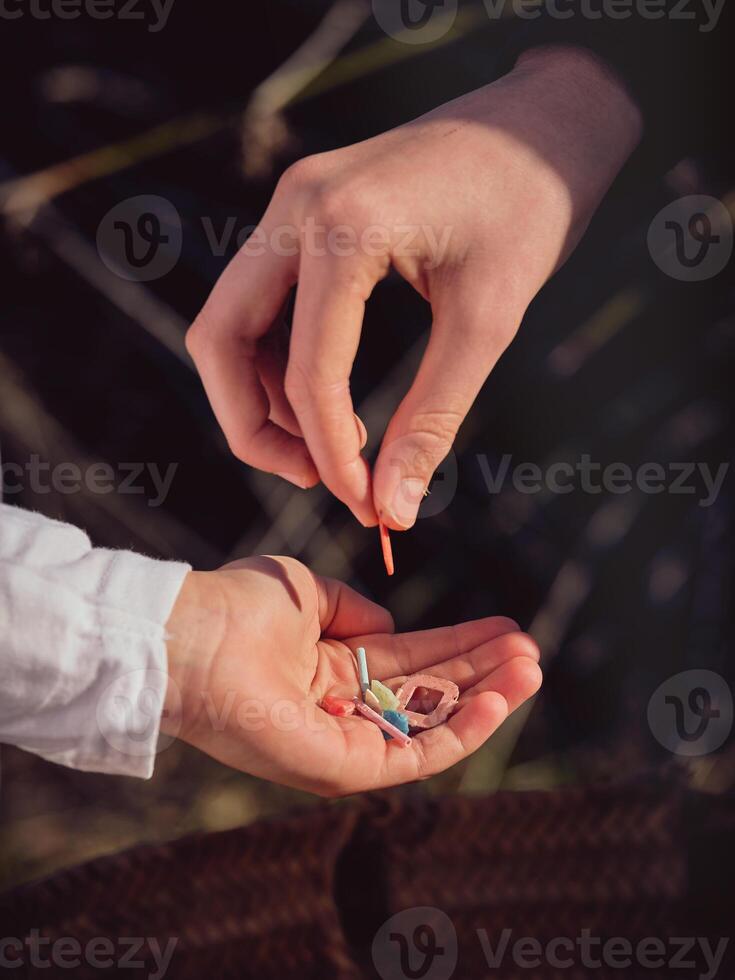 Crop person putting pieces of plastic in hand of boy photo