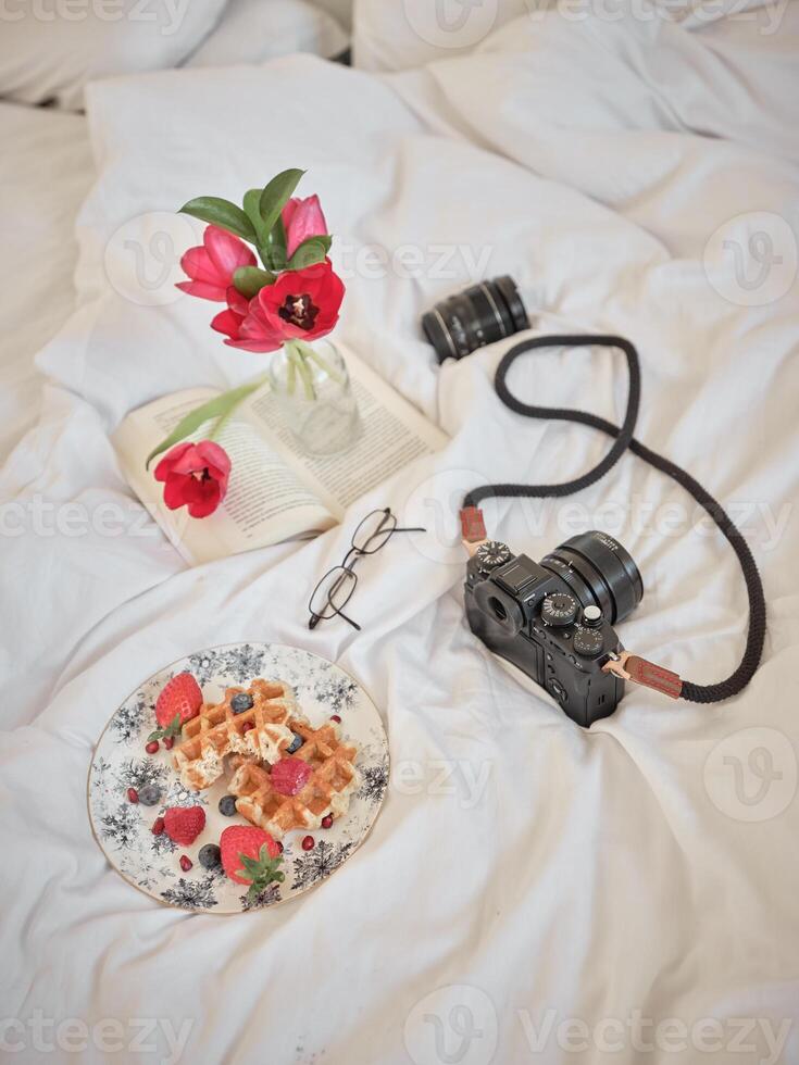 Waffles with photo camera and smartphone on bed