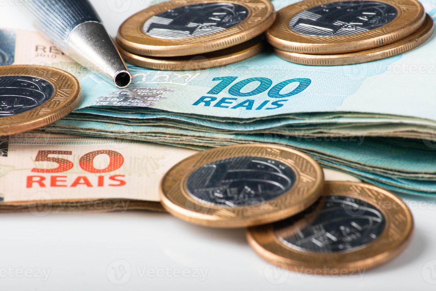 Close-up shot of Brazilian Real banknotes and coins with a pen, illustrating finance, economy, or business concepts in Brazil. photo