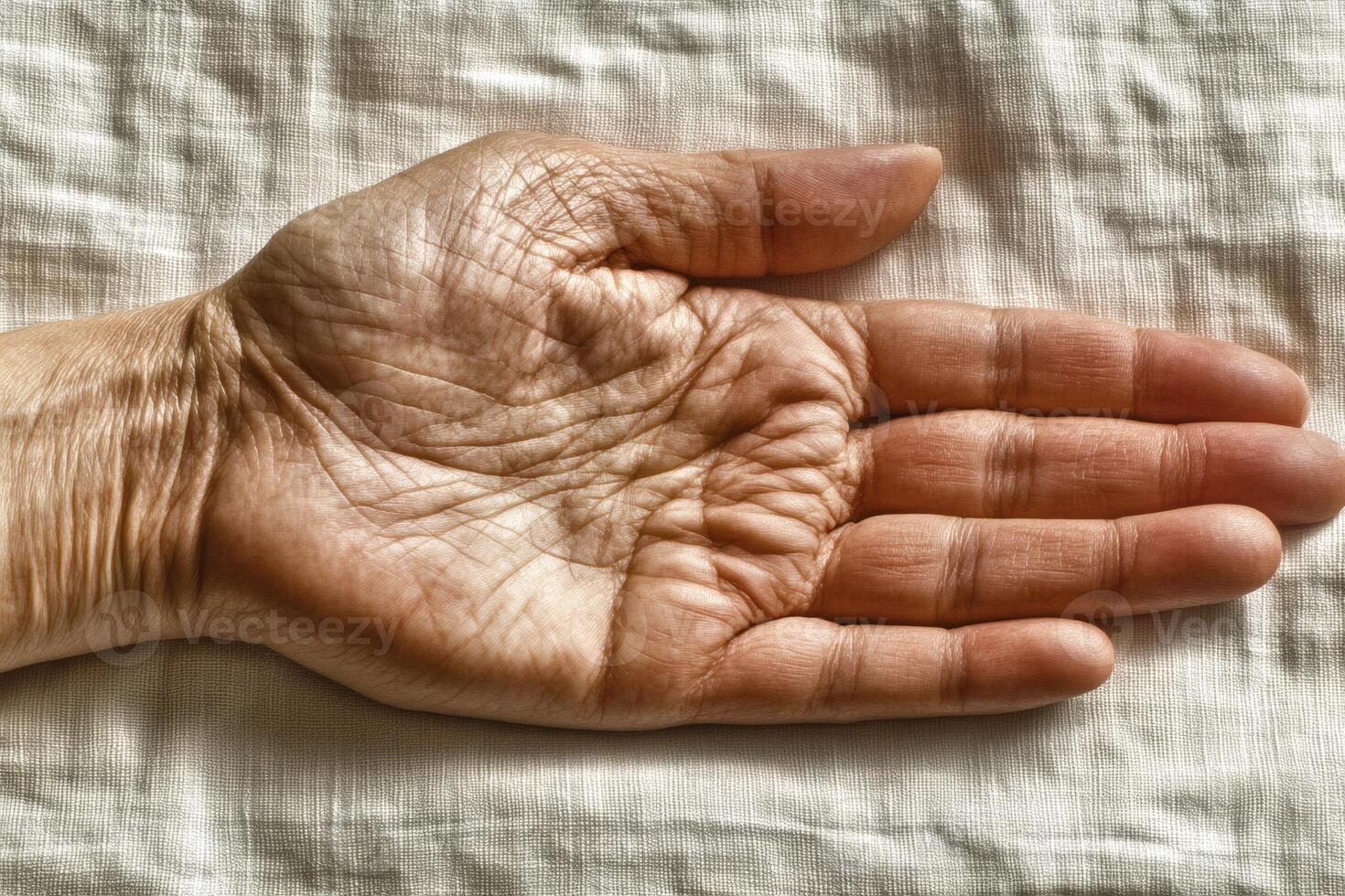 Detailed view of an open hand showing age lines and textures on a light fabric background, highlighting the beauty of human skin photo