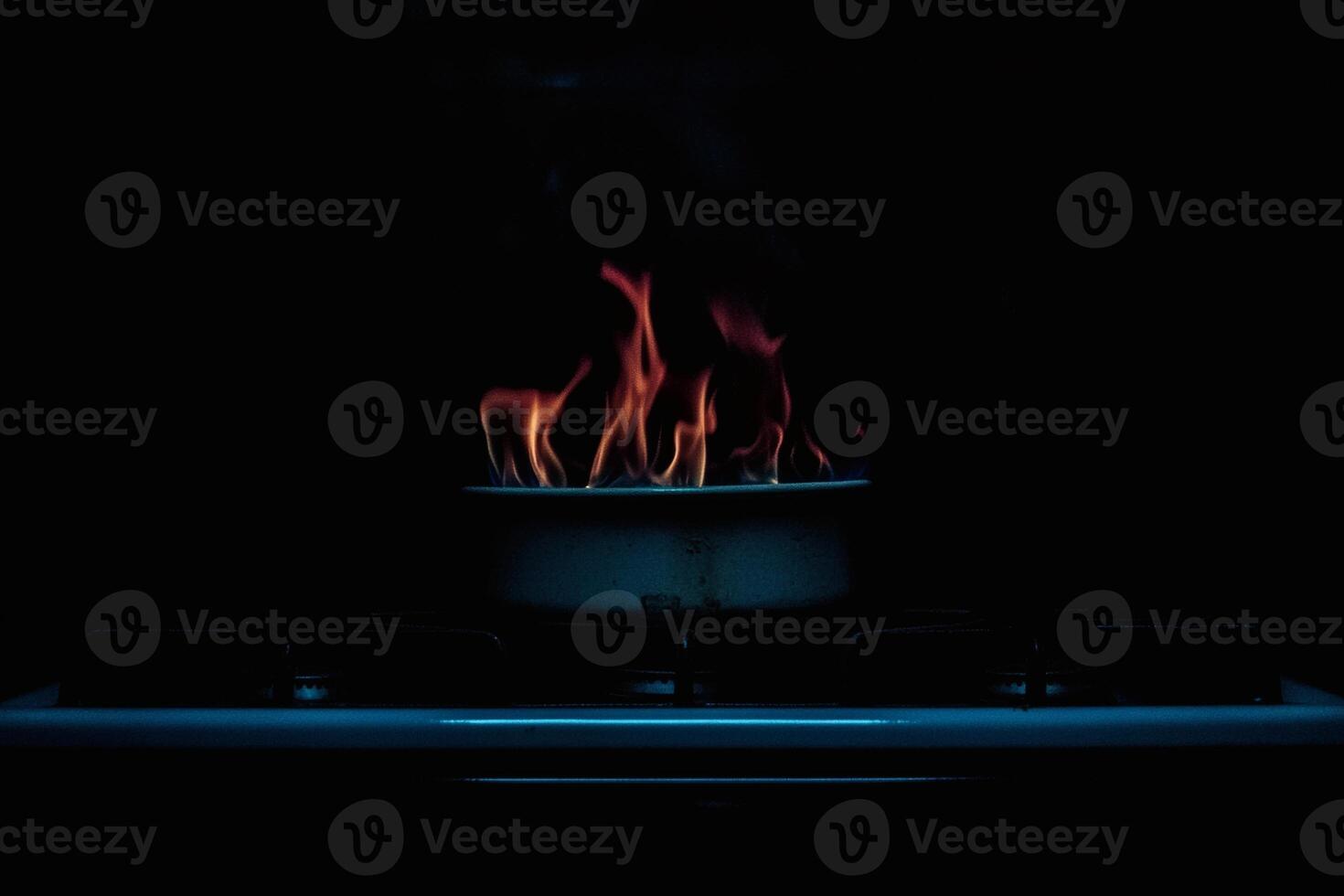 Fire dances on the stove in a dark kitchen. photo