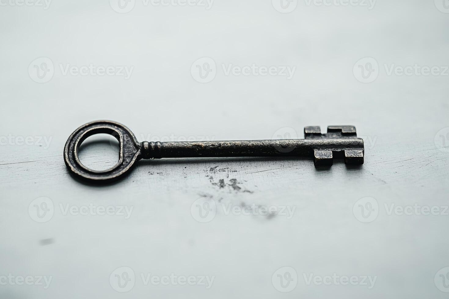 Historic iron key rests on a weathered surface. photo