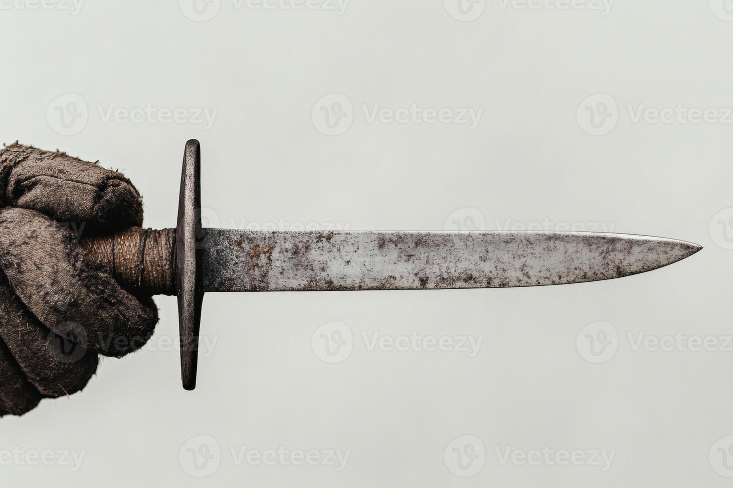 Hand gripping an ancient dagger with a weathered blade. photo