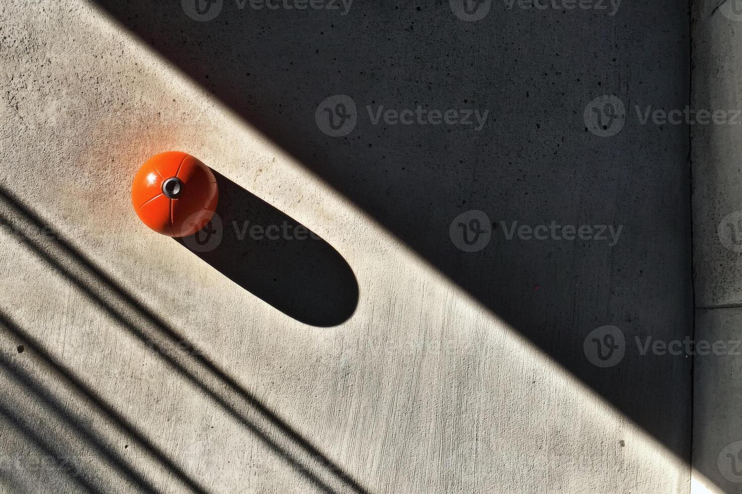 Bright orange object casts a dramatic shadow on concrete. photo