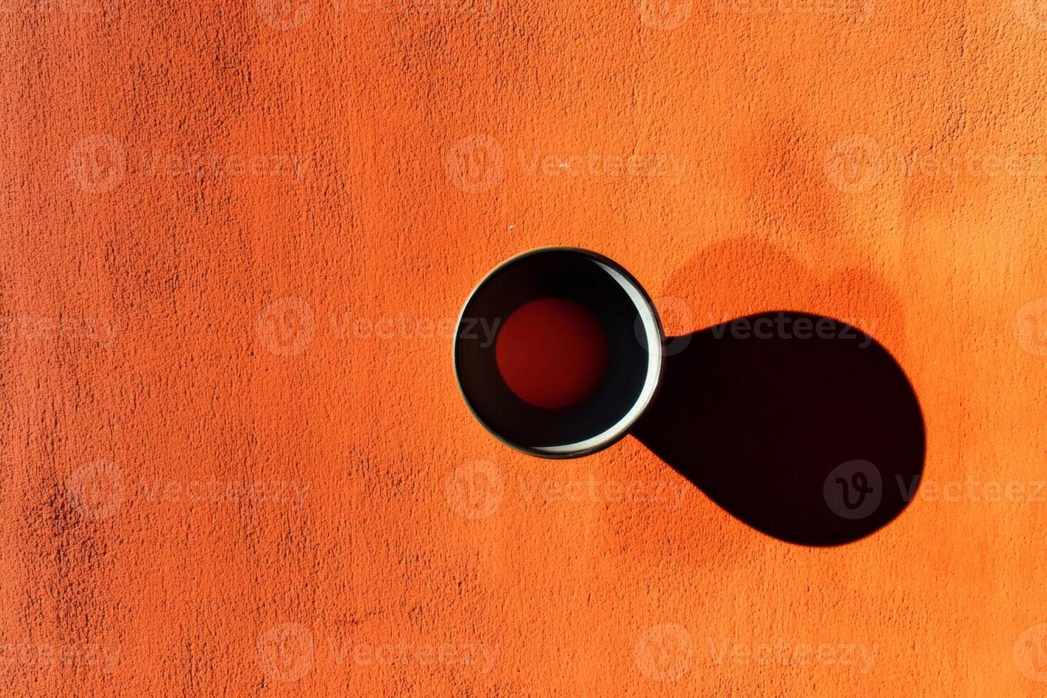 Coffee cup casting a shadow on vibrant orange surface. photo