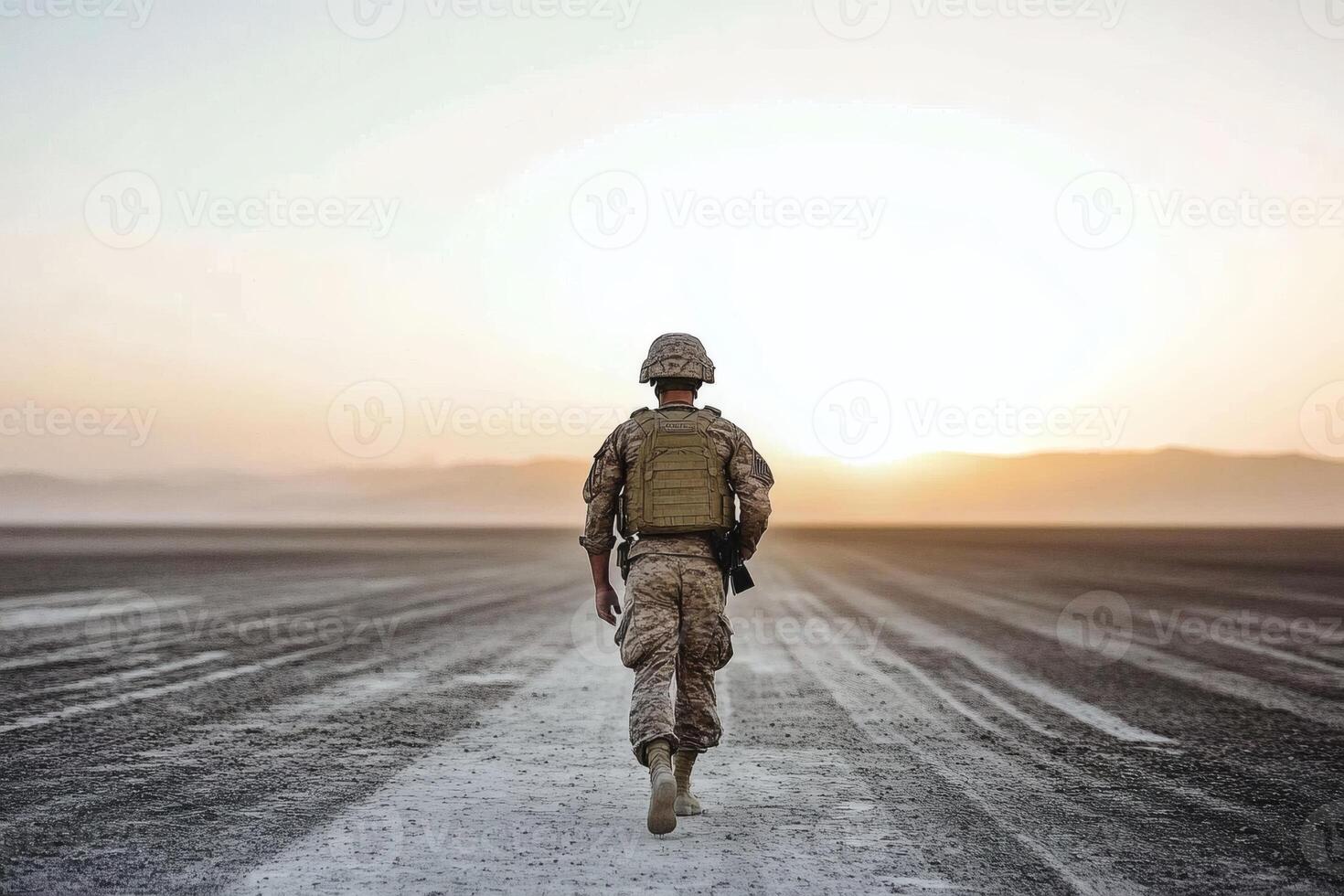 Soldier walks towards the horizon at dawn on a vast desert landscape. photo