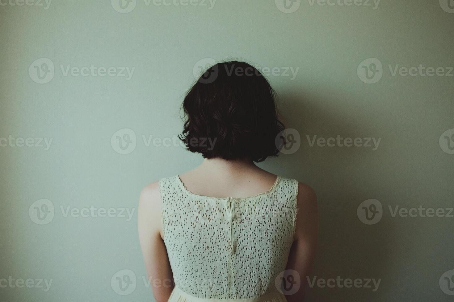 Woman in a delicate dress gazes at a simple wall photo