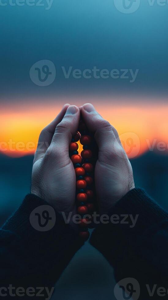 Hands holding prayer beads during sunset photo