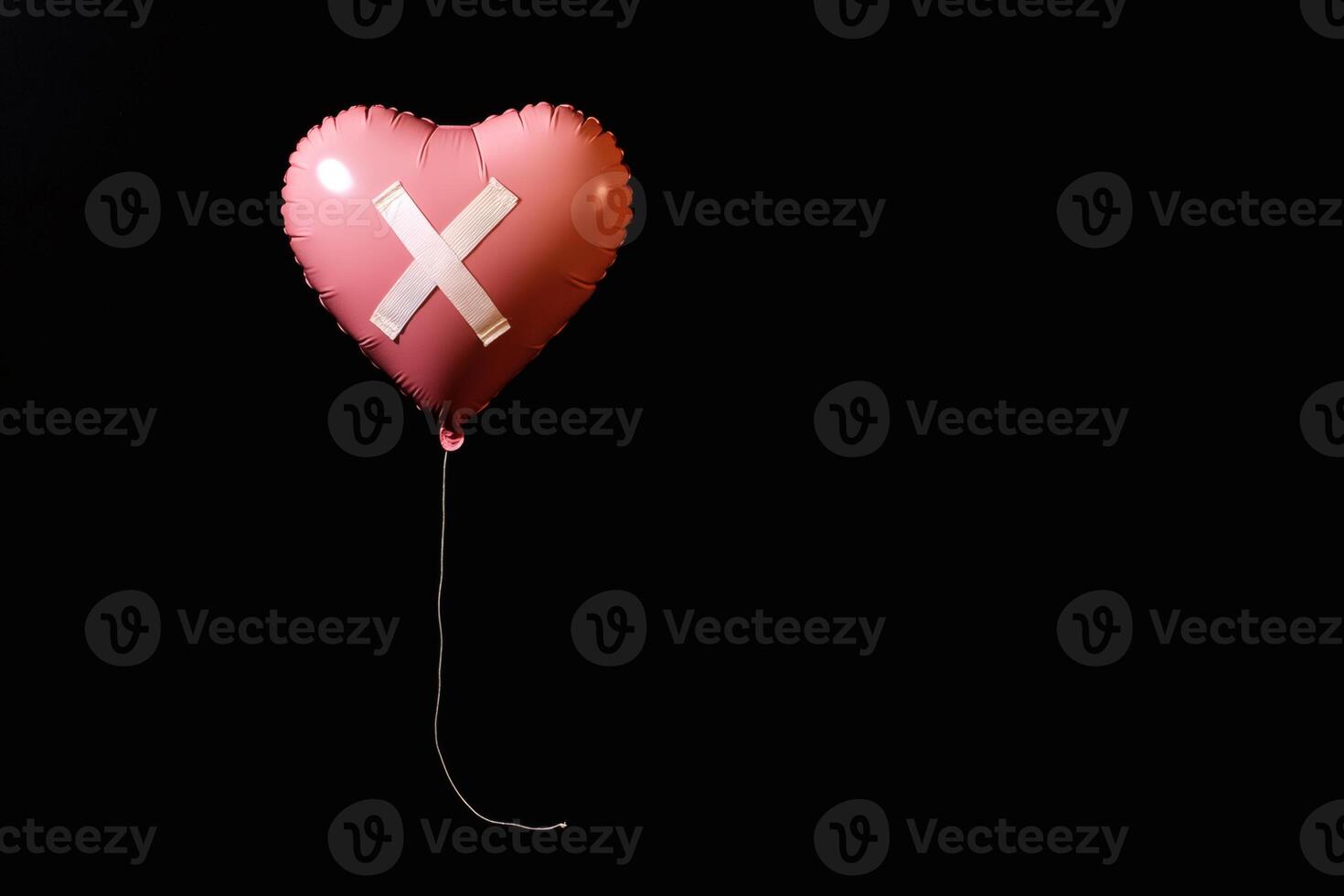 Heart-shaped balloon with an X symbol floating against a black backdrop evokes feelings of loss and longing in an artistic composition photo