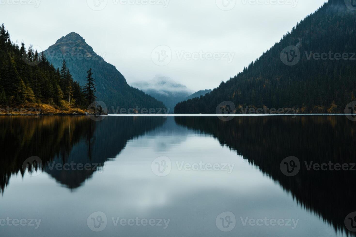 Serene mountain landscape reflects in tranquil lake under a cloudy sky at dusk photo