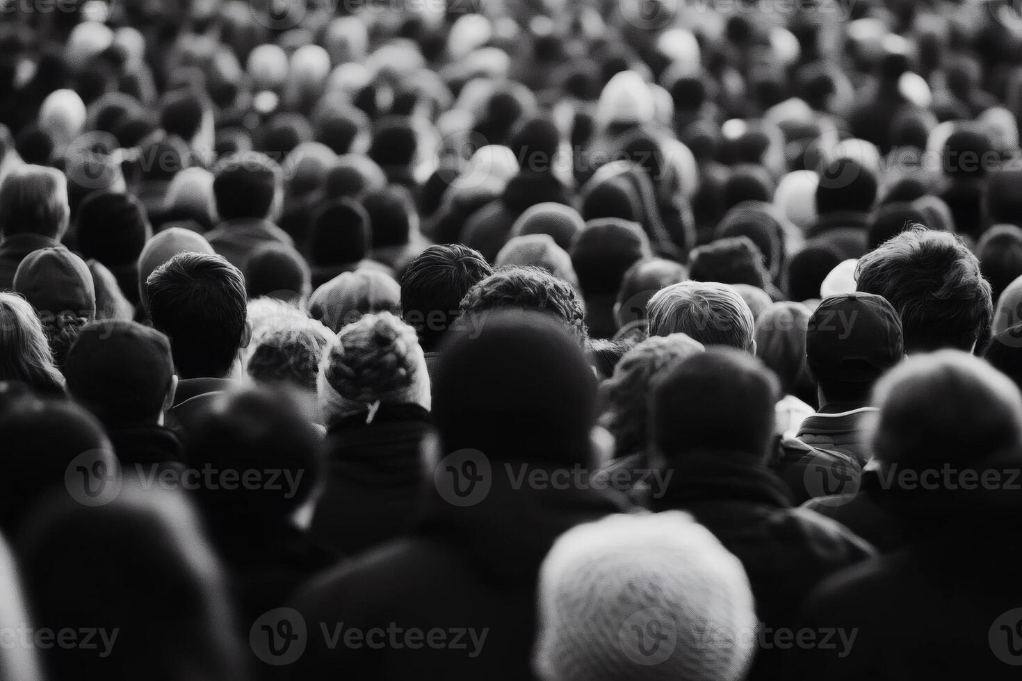 Crowds gather in anticipation at a large outdoor event on a cool evening, creating a sea of diverse expressions and energy photo