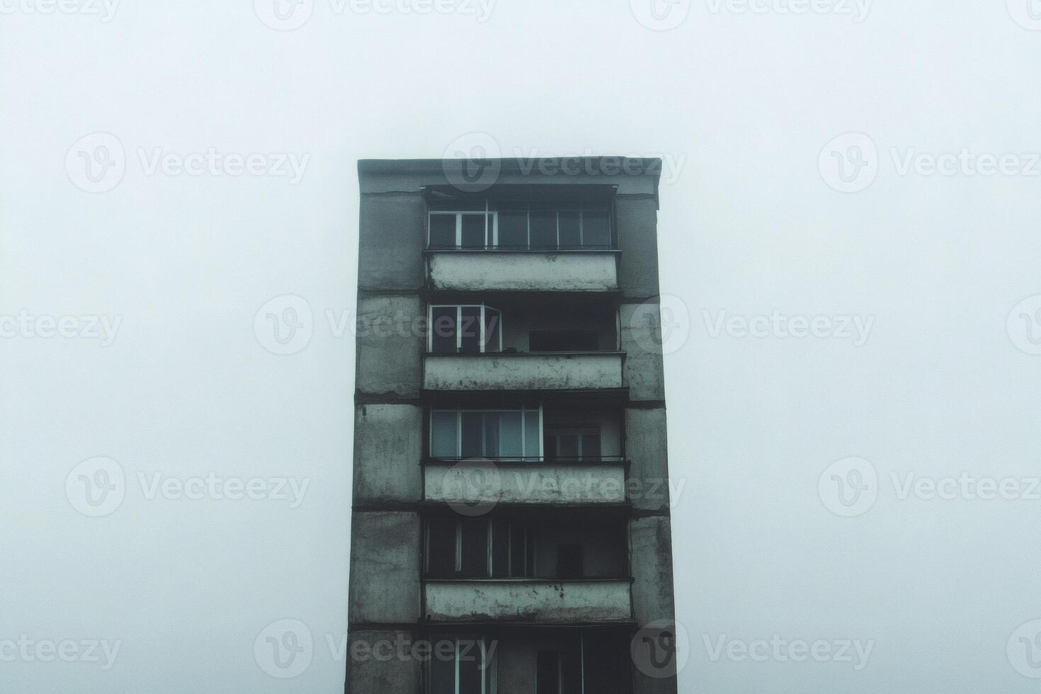 Foggy morning reveals a solitary high-rise building standing tall against a gray sky photo