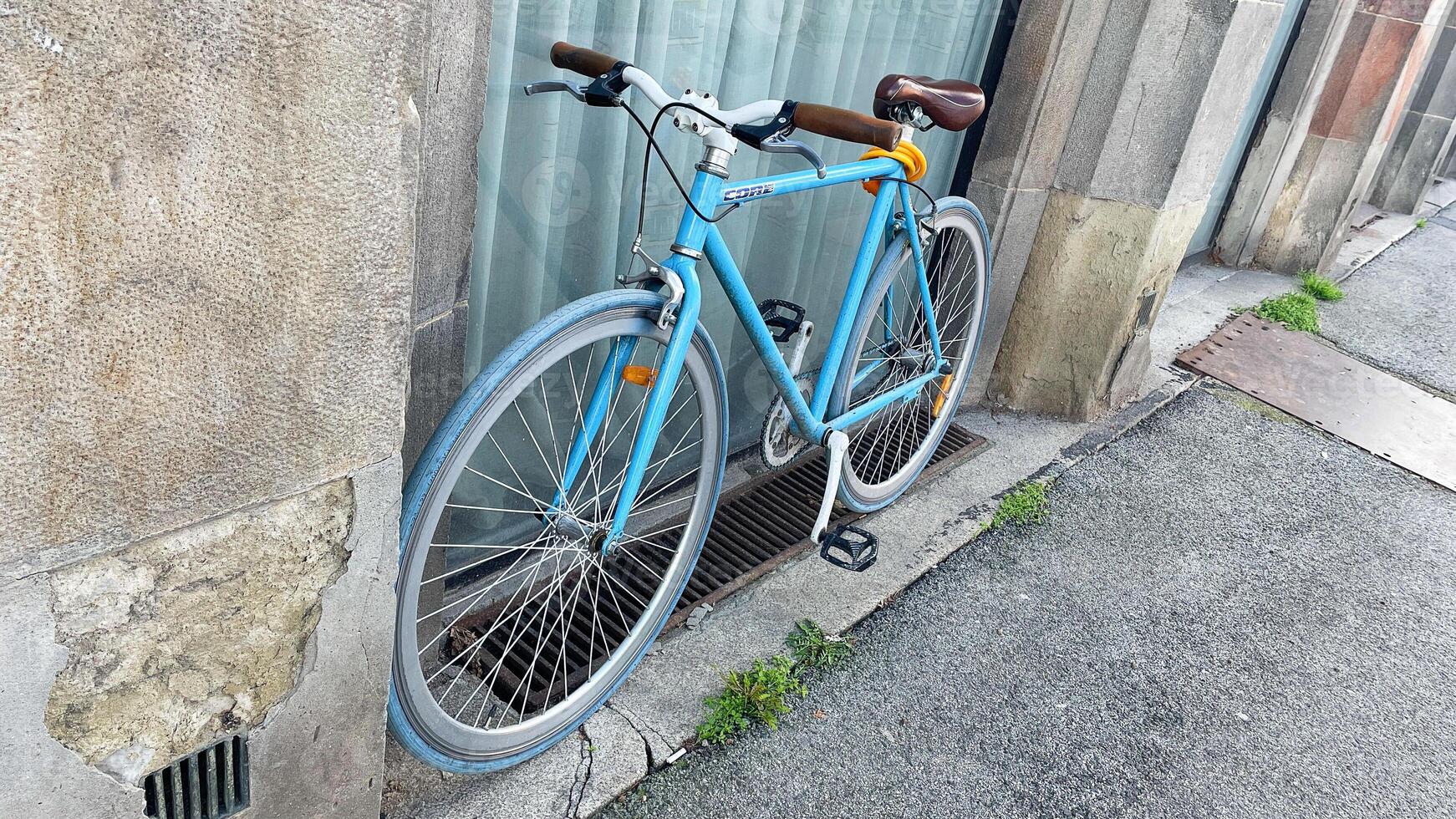 Bright blue bicycle resting against an urban wall photo
