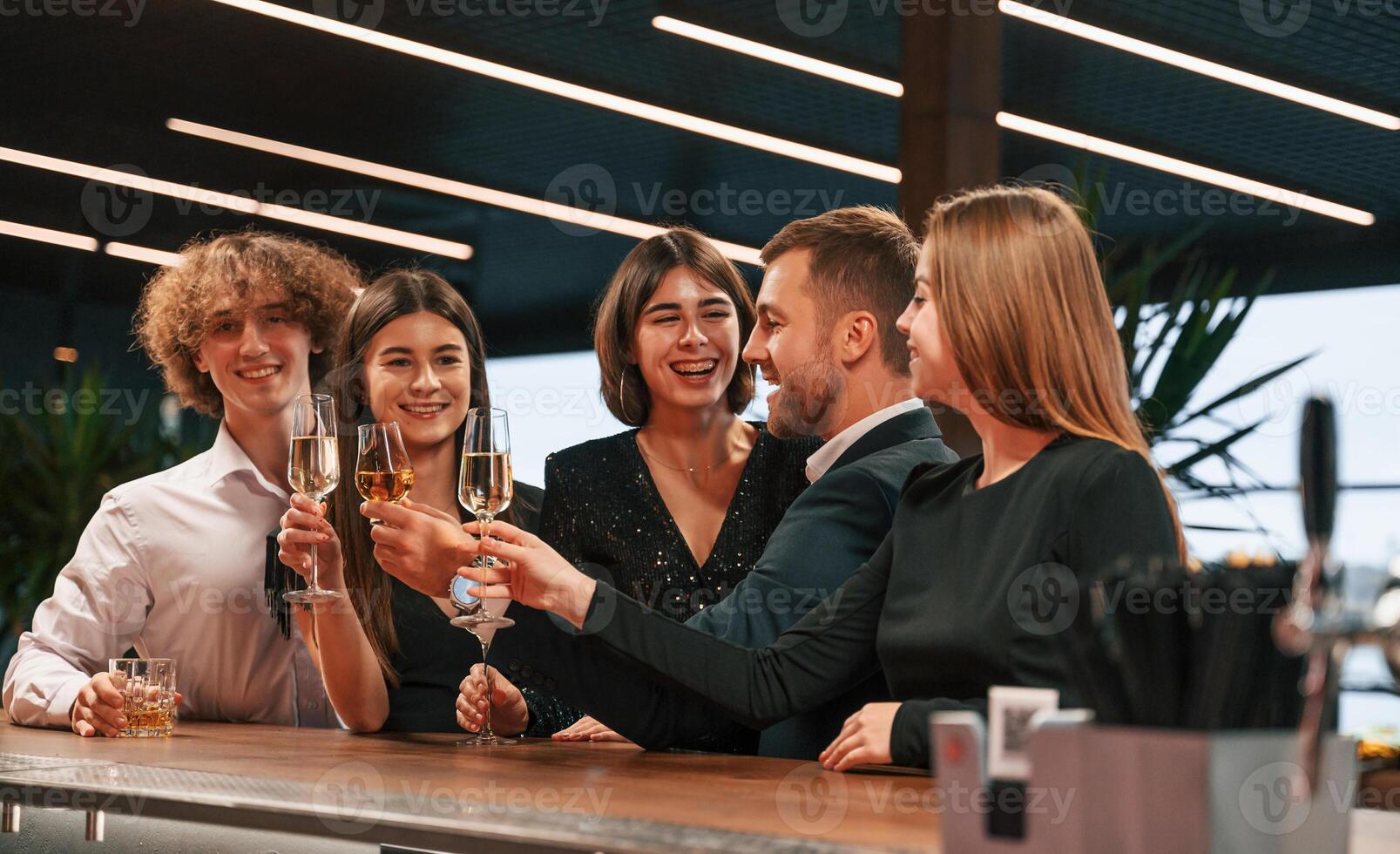 Sitting by the bar table. Group of people in ,beautiful elegant clothes are celebrating New Year indoors together photo